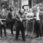 A black and white portrait of a group of people posing at a wedding.