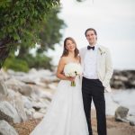 A couple poses for a wedding portrait on the beach.