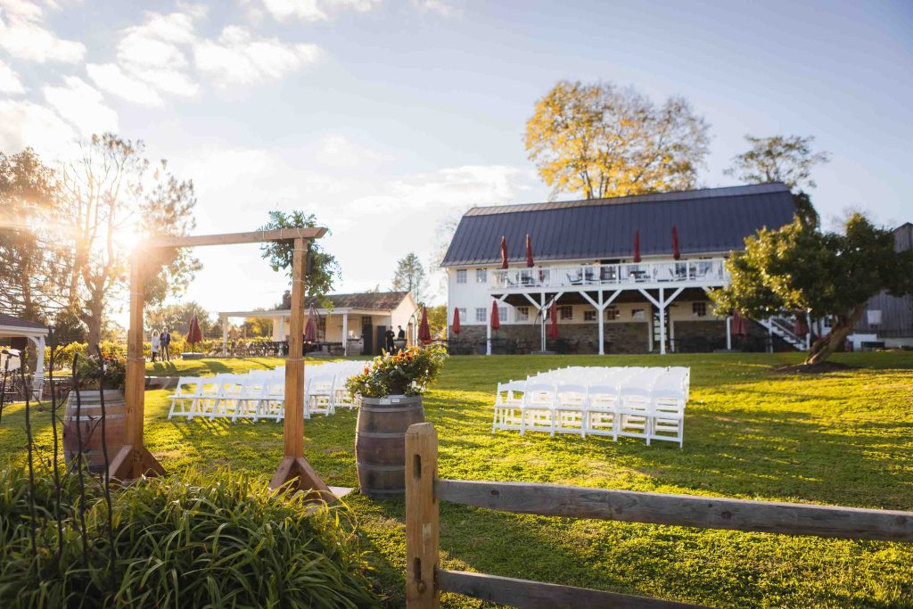 A detailed wedding ceremony set up in a field with white chairs.
