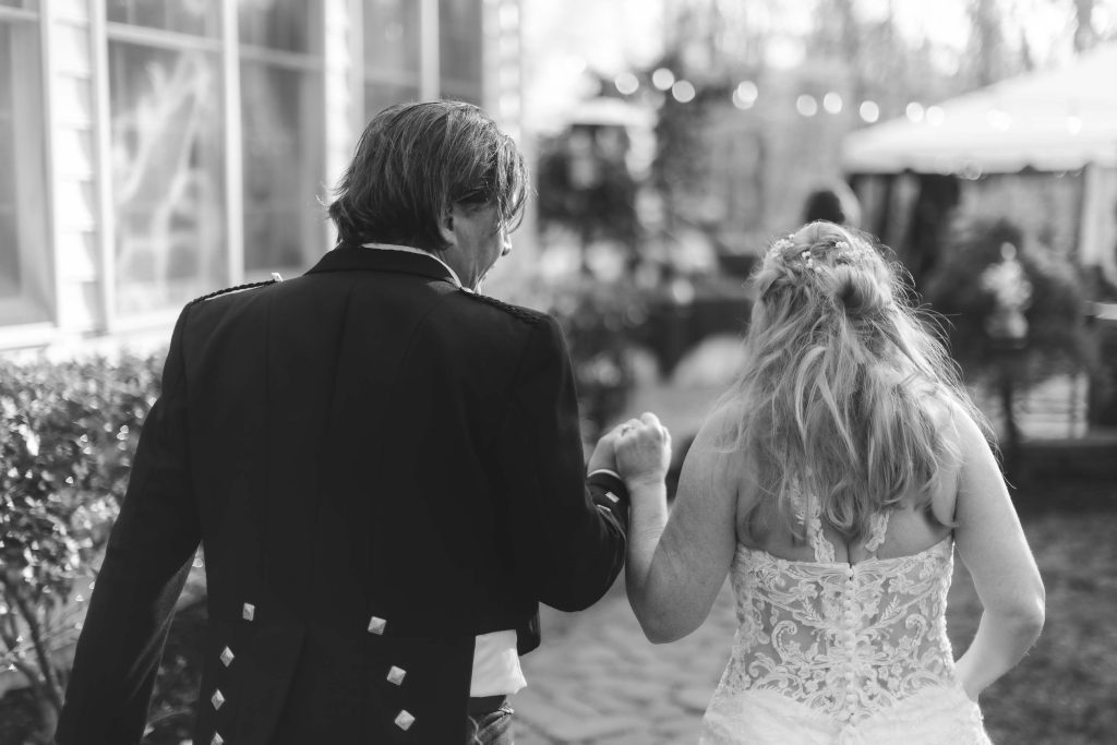 Black and white photo of bride and groom holding hands during their wedding ceremony.