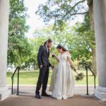 A wedding portrait of a bride and groom in front of pillars.