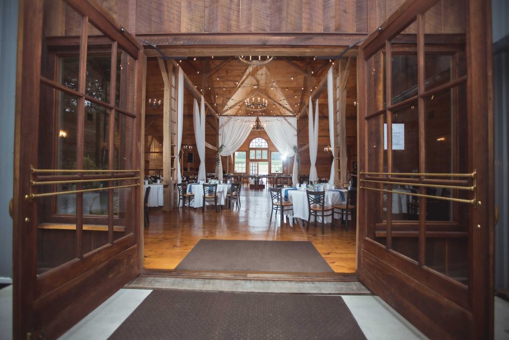 A detailed wooden door leading into a room with tables and chairs, perfect for a wedding venue.