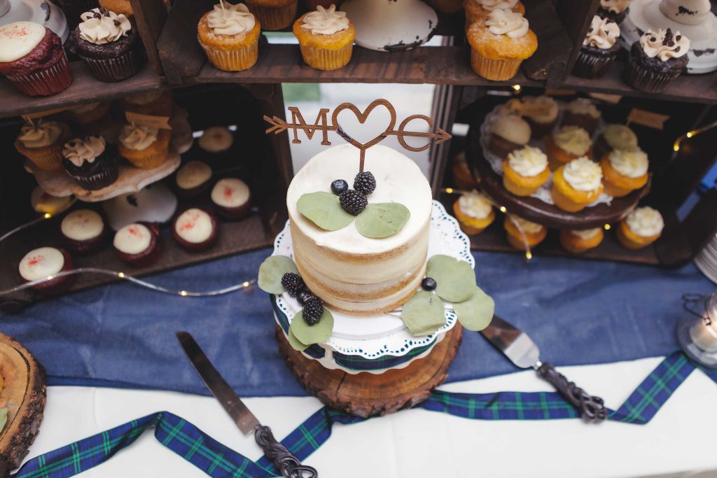 A detailed wedding cake with cupcakes displayed on a table.