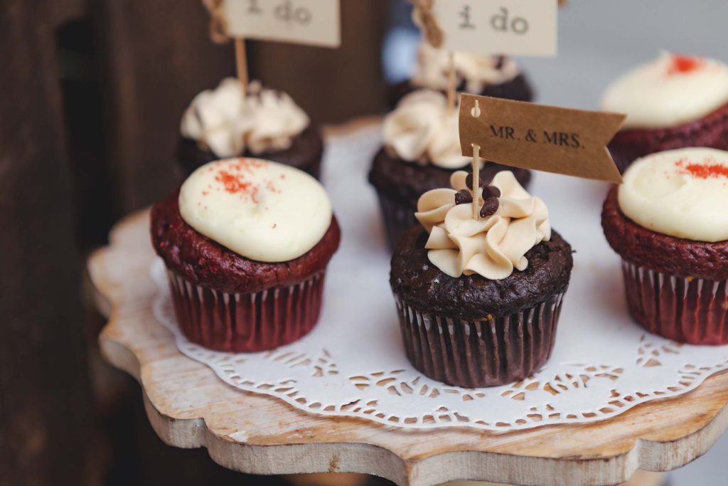 Red velvet cupcakes on a wedding cake stand with intricate details.