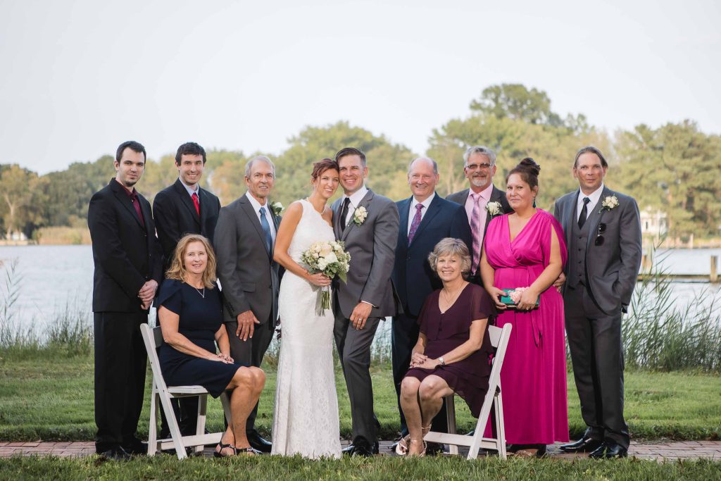 A wedding party posing for a portrait by a lake.