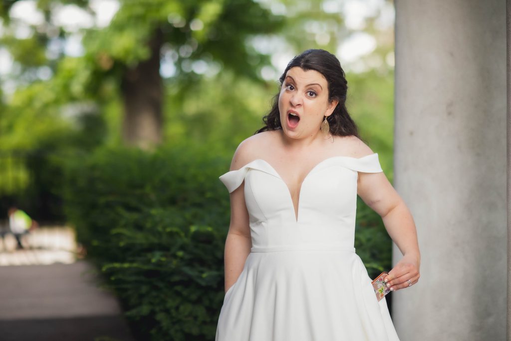 A surprised bride in a white wedding dress.