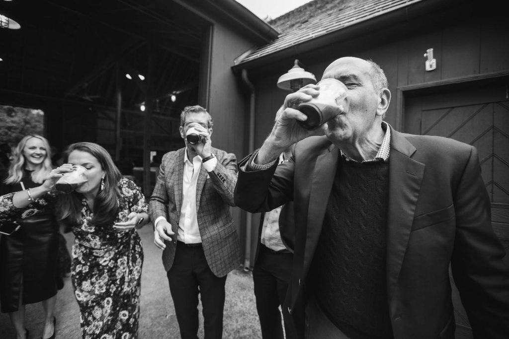 A black and white photo of a group of people drinking at a wedding reception.