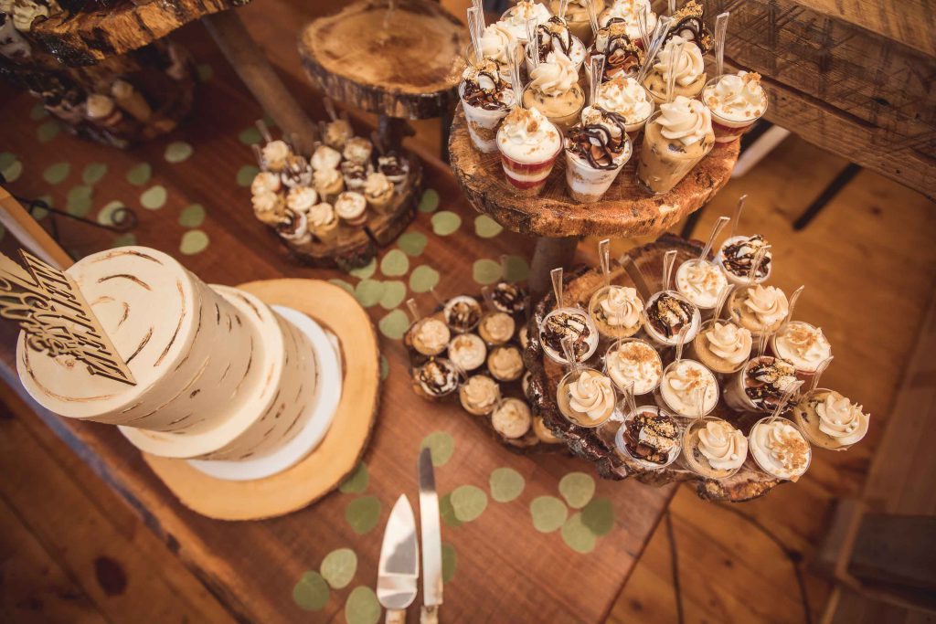 A table full of wedding desserts on top of a wooden table.