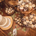 A table full of wedding desserts on top of a wooden table.