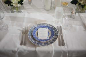 A wedding table setting with blue and white plates and silverware.