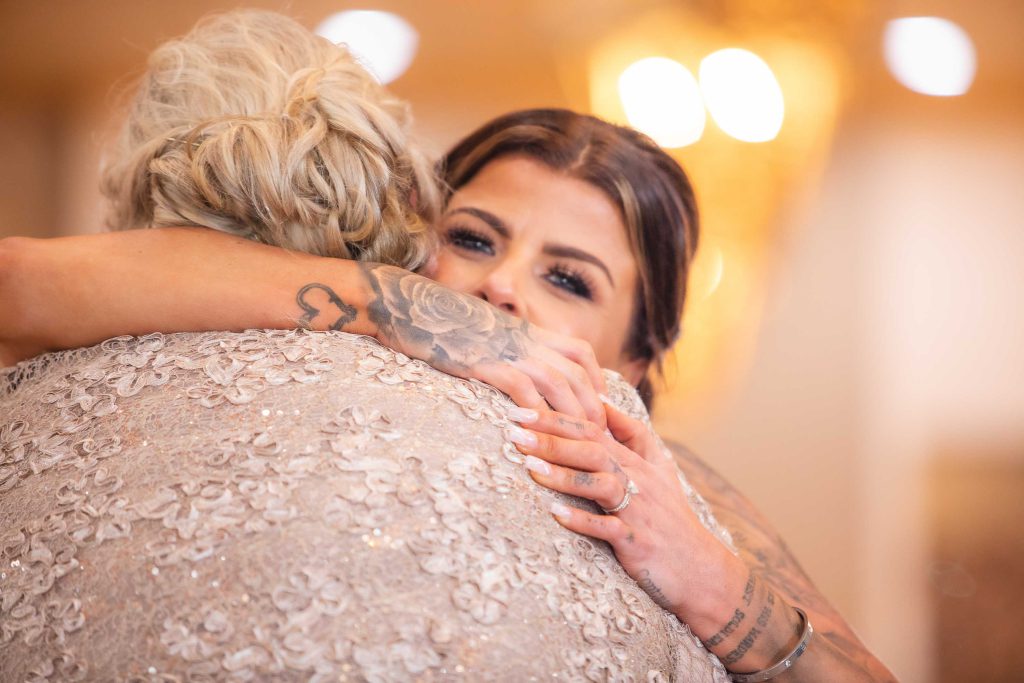 A woman is hugging her mother at a wedding reception.