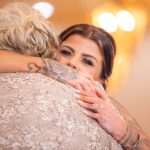 A woman is hugging her mother at a wedding reception.