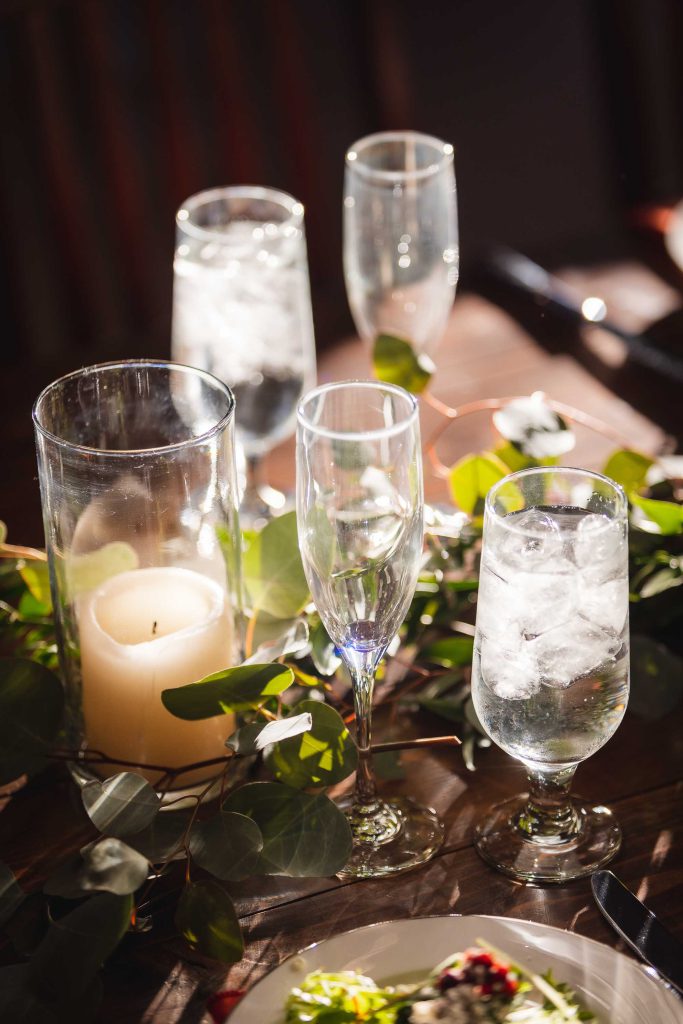 A wedding table setting with candles, eucalyptus leaves, and intricate details.
OR
A wedding table setting with elegant candle arrangements and eucalyptus leaves.