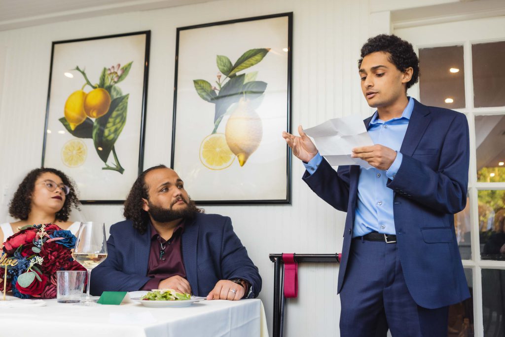 A man is giving a wedding speech at a restaurant reception.
