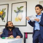 A man is giving a wedding speech at a restaurant reception.