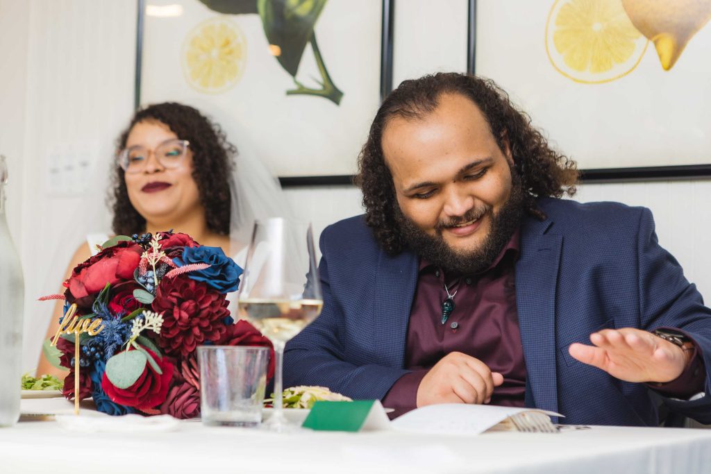A man and a woman sitting at a table at a wedding reception.