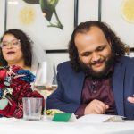 A man and a woman sitting at a table at a wedding reception.