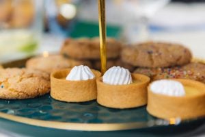 A tray of desserts on a green plate with wedding details.
