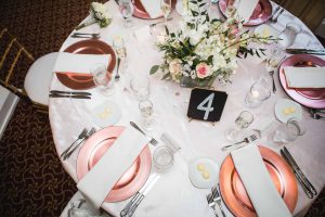 Details of a round table set with pink and white plates for a wedding.
