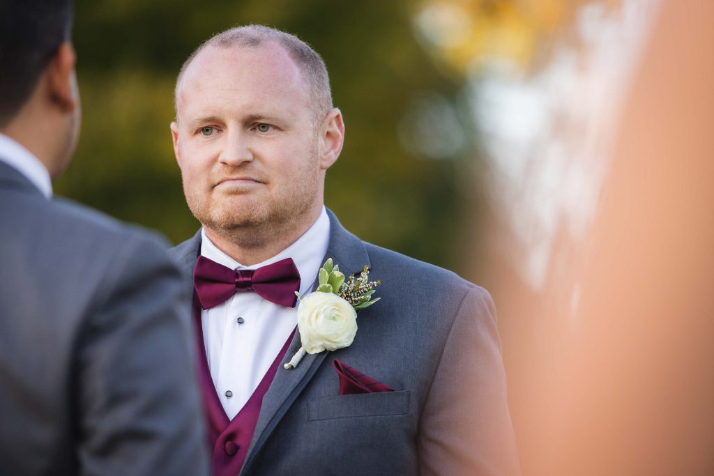 A man in a suit is looking at another man during a wedding ceremony.