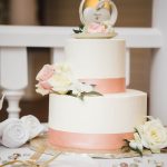 A detailed white and pink wedding cake on a table.