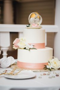 A detailed white and pink wedding cake on a table.