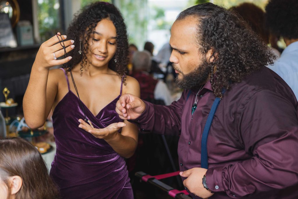 A man is helping a woman with her hair for a wedding reception.