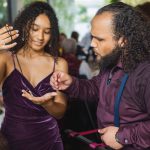 A man is helping a woman with her hair for a wedding reception.
