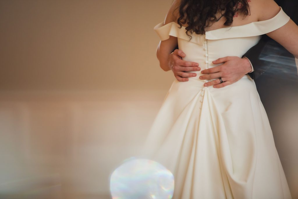 A bride and groom hugging at their wedding reception in front of a mirror.