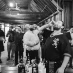 A black and white photo of a group of people at a wedding reception in a barn.