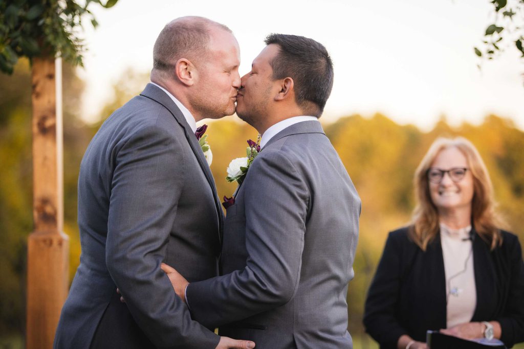 During their outdoor wedding ceremony, a groom affectionately kisses his bride.