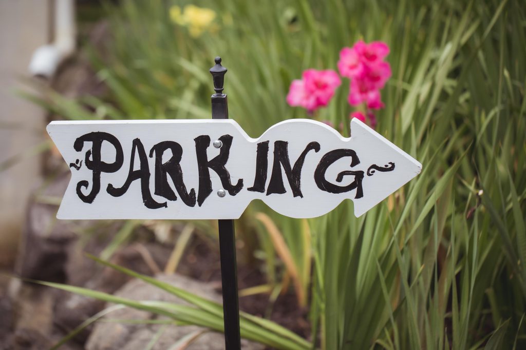 A sign displaying wedding details in front of flowers.