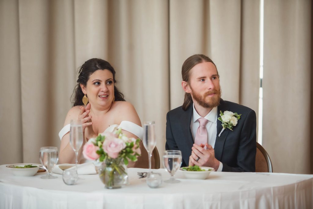 A couple sitting at a reception table during their wedding.