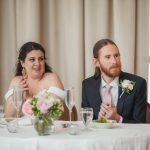 A couple sitting at a reception table during their wedding.