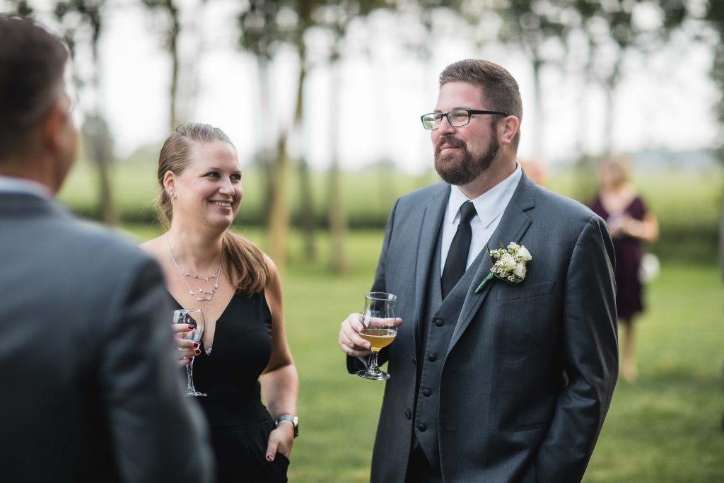A man in a suit and tie is talking to a woman at a wedding reception.