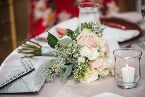 A wedding table setting with elegant silverware and a beautiful bouquet centerpiece.