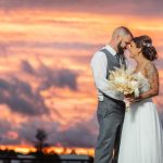 A wedding couple share a sunset portrait.