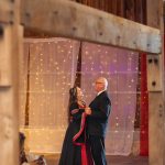 A newlywed couple dancing at their wedding reception in a barn.