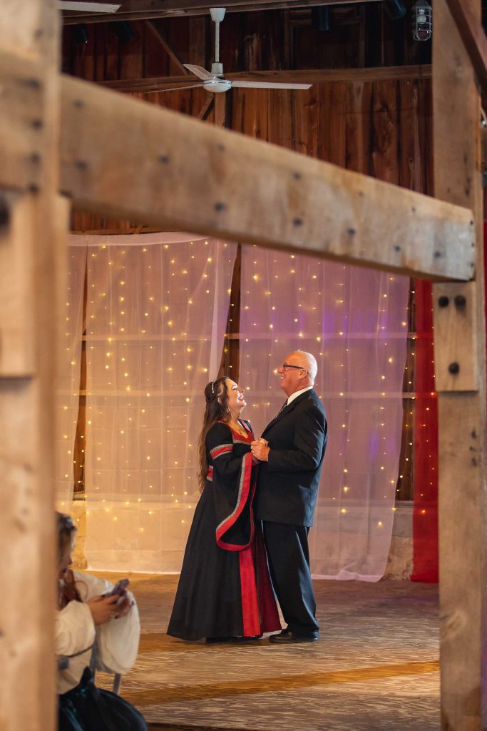 A newlywed couple dancing at their wedding reception in a barn.