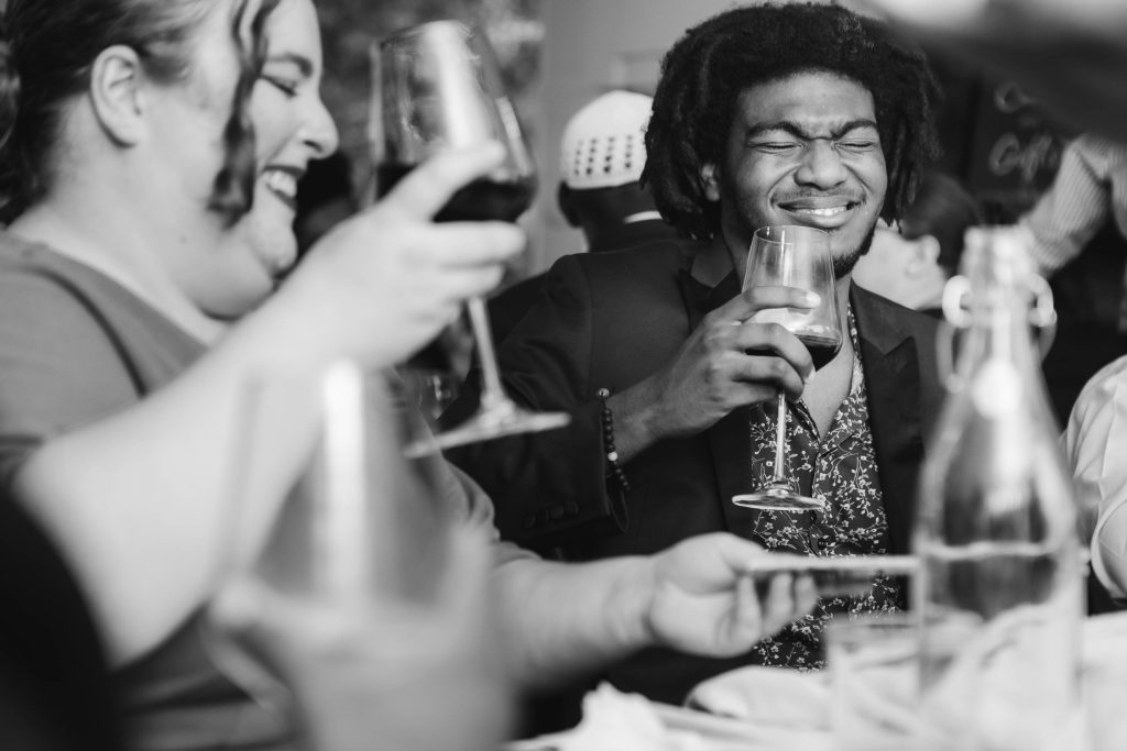 A black and white photo of a wedding reception with people drinking wine.