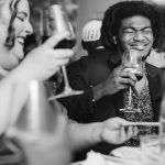 A black and white photo of a wedding reception with people drinking wine.