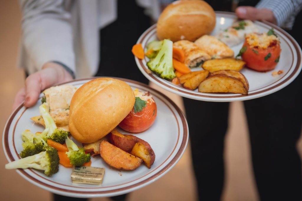 Two people holding plates with wedding food on them.