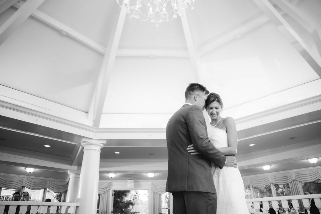 A bride and groom embrace at their wedding reception in the lobby of a hotel.