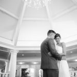 A bride and groom embrace at their wedding reception in the lobby of a hotel.