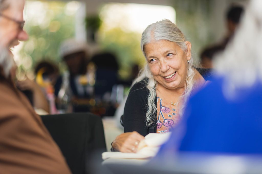 An older woman smiles at a wedding reception.