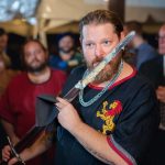 A groom holding a sword during his wedding reception.