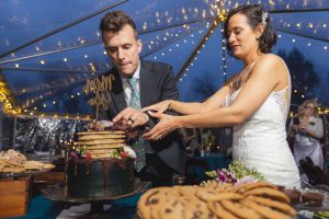 A wedding reception with a bride and groom cutting a cake in a tent.