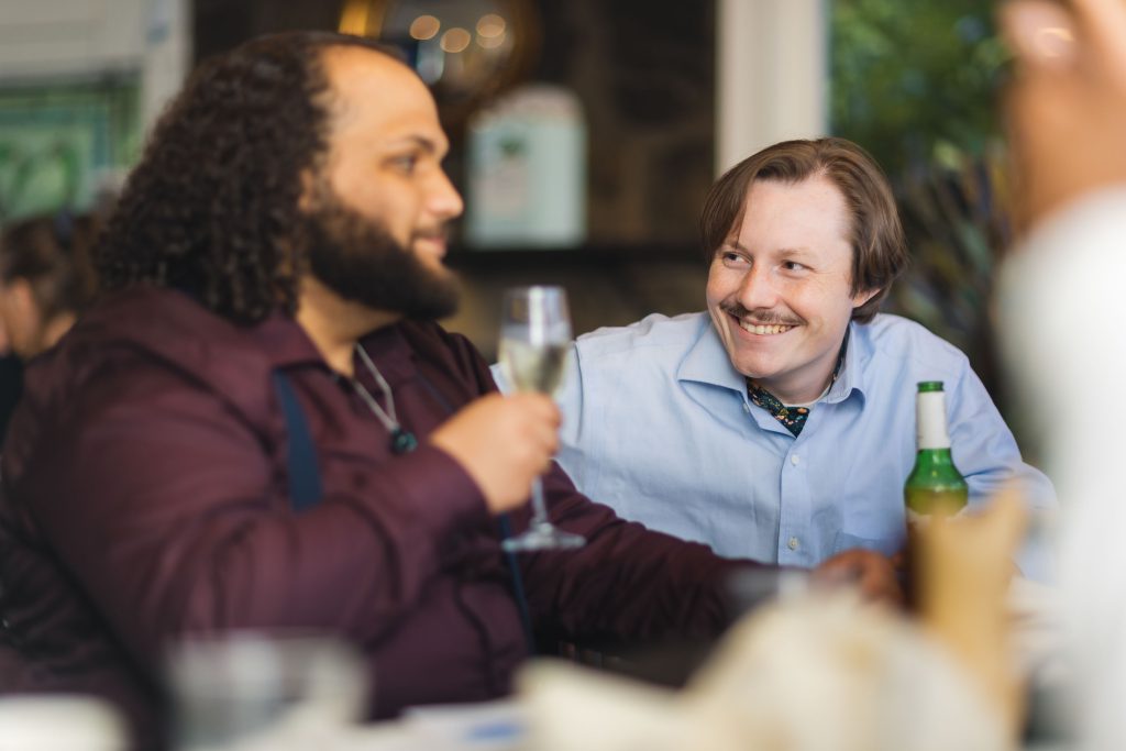 Two men laughing at a wedding reception table.