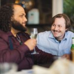 Two men laughing at a wedding reception table.