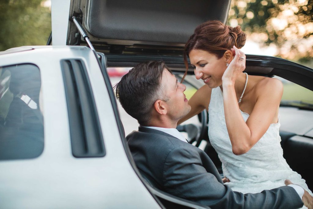 A wedding portrait featuring a bride and groom in the trunk of a car.